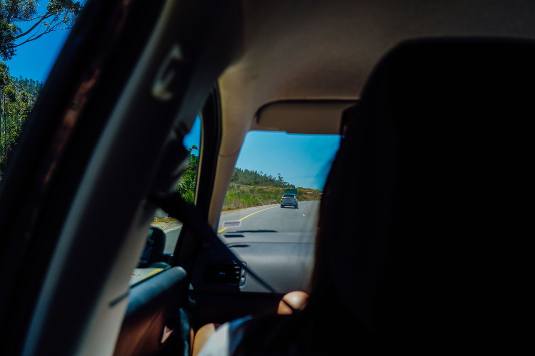 A scenic road viewed through the inside of a car.