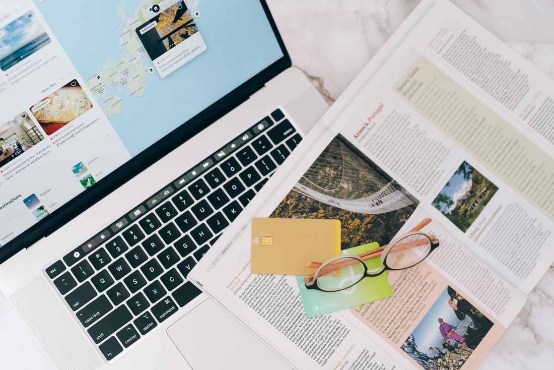 A laptop, map and travel-planning materials on a table.