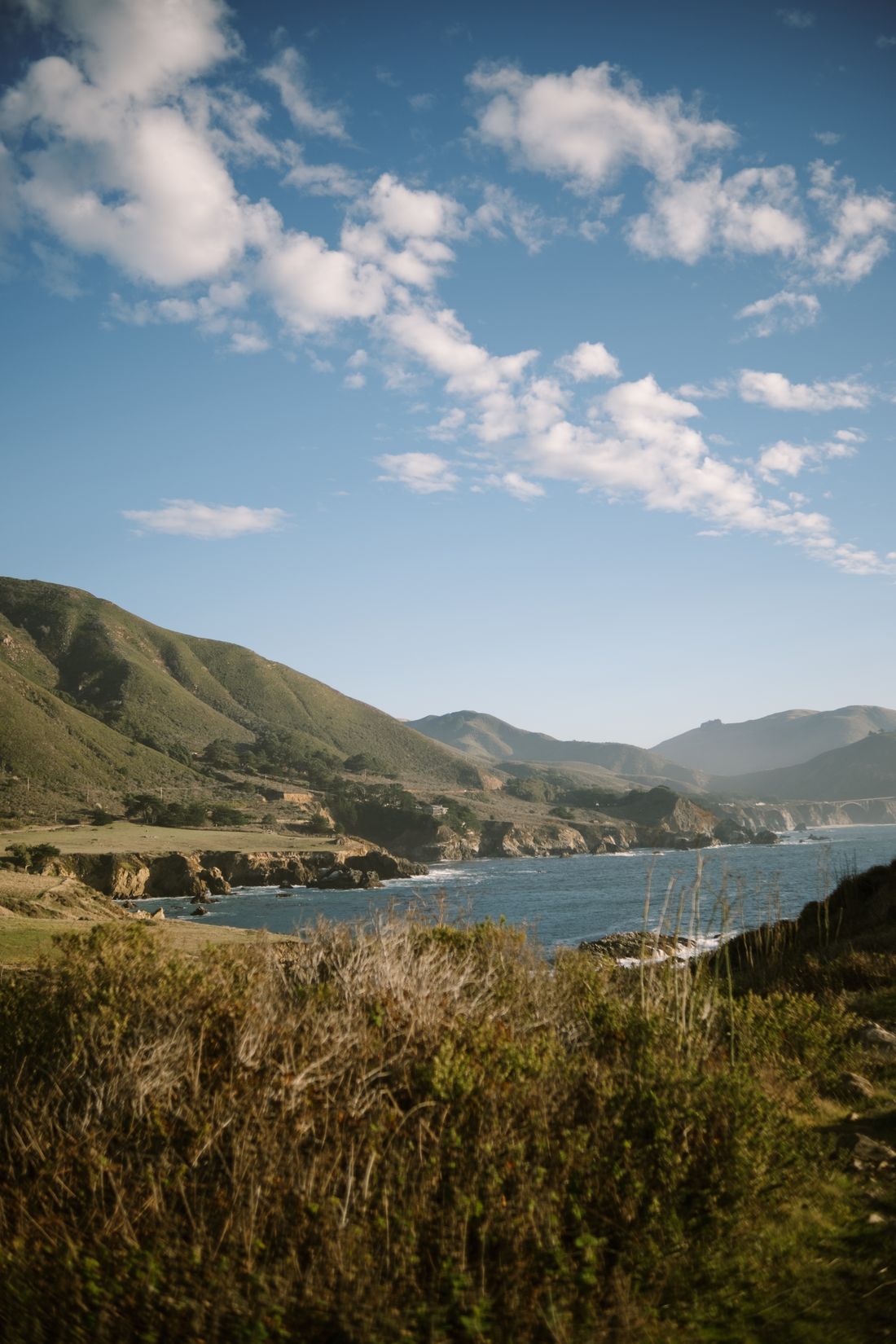 A coastal view of Big Sur with rolling hills and blue water.