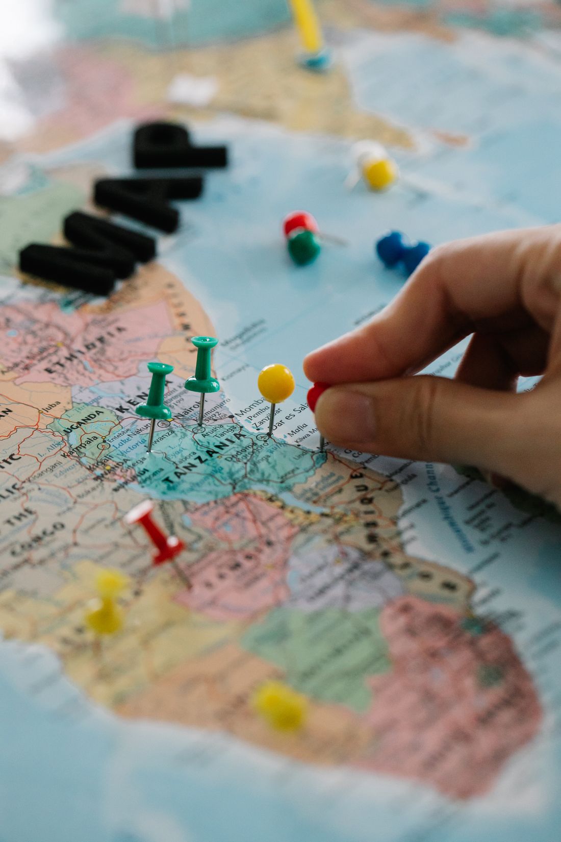 A hand placing location pins on a map.